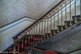 <center> Hôtel Chambon. </center> Escalier d'honneur. Rampe en fonte en motif de crosse d'évêque. Derrière le fauteuil, escalier qui descend aux basses offices.