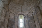 Saint-Trinit.<br> Les pilastres massifs,  surmontés de petites arcatures aveugles,  descendent jusqu’au sol et occupent les angles du pentagone. Une baie axiale, très ébrasée vers l’intérieur et décorée extérieurement, éclaire le sanctuaire qu’illumine le soleil levant. Le décor des chapiteaux se réduit aux ornements qui constituent généralement, dans le chapiteau corinthien d’époque romane, la partie inférieure et la partie supérieure de la corbeille.