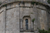 Saint-Trinit.<br> Les pilastres sont surmontés de triglyphes au-dessus desquels prennent place de discrets segments de frise de dents d'engrenage. La fenêtre absidiale est entourée de courtes colonnettes surmontées de chapiteaux ornées de feuilles d'acanthe. Cette baie est identique à celle de la façade méridionale, mais traitée avec infiniment plus de simplicité : les fûts des colonnettes — qui s’appuient ici sur une petite corniche débordante lancée entre les deux pilastres axiaux — sont lisses et la voussure qu’elles supportent non décorée.
