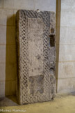 Eglise Saint Andéol. <br> Pierre tombale de l'évêque Bernoin, mort en 874. Celle-ci porte une épitaphe dont le texte a été ainsi restitué (R. Saint-Jean) : Ici se trouve la tombe de l'évêque Bernoin qui découvrit le corps du bienheureux Andéol martyr et qui construisit cette maison [l'église] depuis ses fondations. Il dirigea l'Église de Viviers durant 23 ans et mourut dans la paix le 5 des ides de décembre.  L'épitaphe est entourée d'une bande ornée d'entrelacs.