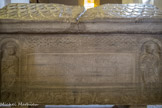 Eglise Saint Andéol. <br> Au centre une longue inscription latine à la gloire du saint et de part et d'autre, deux religieux, saint Polycarpe et saint Bénigne, tenant une tablette entre leurs mains ; ils sont placés sous une arcade en plein cintre à colonnes torsadées à chapiteaux cubiques.  Les entrelacs d’inspiration carolingienne occupent la frise supérieure sous laquelle se trouve
un cartouche conservant une inscription latine : Vous tous qui placez votre espérance en la vie éternelle, regardez ce tombeau à quatre faces : Il est digne de manifester aux quatre parties du monde les merveilles du Christ et d'apprendre aux justes à vaincre dans les combats de la foi. Ô Andéol, heureux martyr, donnez-nous des marques de votre protection. L'enceinte de ce petit tombeau renferme votre corps, mais votre âme vertueuse jouit avec les saints, par delà les astres, de la félicité céleste. Qu'ils accourent
à vous ceux que de cruelles douleurs affligent; il n'est aucun de ceux qui implorent votre protection, qui ne s'en retourne consolé.