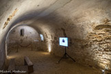 Chapelle des Moines. Berzé. <br> La chapelle basse. La chapelle de l'abbé se compose de deux étages romans. L’étage inférieur est voûté en berceau et date encore du 11e siècle, bien que l’étage supérieur soit de la reconstruction du début du siècle suivant. Le sol semble ne jamais avoir été dallé. Deux petites baies percées dans l’abside permettaient l’apport d’une faible lumière.
Le cul-de-four de l’abside porte encore de nombreuses traces de polychromie datées du tout début du XIVe siècle : une frise et des décors de joints ocre rouge dessinent un faux appareil  régulier. Les fonctions de cette chapelle restent encore imprécises.