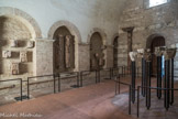 Saint-Philibert de Tournus. Le Musée Lapidaire.<br> Ce petit Musée Lapidaire est  aménagé dans le chauffoir, petite salle romane du 12e siècle avec une voûte en berceau et des arcatures murales. On y présente  plusieurs chapiteaux du cloître, provenant des galeries, détruits et retrouvés plus tard. Les chapiteaux du 12e siècle, mutilés, présentent des scènes bibliques et évangéliques qui sont les plus importantes sculptures historiées de Tournus. On y trouve les thèmes classiques des sculpteurs romans : la Création, la Nativité et l’Annonce aux Bergers, Daniel dans la fosse aux Lions, le Paradis Terrestre, la Procession des Apôtres, l’Entrée du Christ à Jérusalem le jour des Rameaux, la Résurrection du Christ avec les Saintes femmes, une guérison et l’Adoration des Mages. Le style des chapiteaux, étonnant en Bourgogne, se rapproche de celui de l’école romane du Midi. Contre le mur du fons, une cariatide du clopcher.