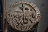 Cluny. <br> Salle de l’avant-nef. L’avant-nef de la grande église abbatiale Cluny III était un lieu de transition entre le monde profane et le monde sacré. Elle accueillait les fidèles et les processions monastiques, mais c’est également le seul endroit de l’église qui était accessible aux catéchumènes (les non baptisés). <br> Clef de voûte de l’agneau pascal qui se trouvait à l'aplomb du portail. XIIe siècle. Calcaire. Sur la tarage bordure circulaire, on peut lire, écrit en lettres onciales, l'inscription : grand dans le ciel, ici sculpté comme un petit agneau.
