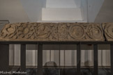 Cluny. <br> Frise de l’avant nef. XIIe siècle. Elle est composée de médaillons reliés entre eux par une bague dite d’orfèvrerie lisse décorée de diverses manières. Dans les médaillons sont inscrits des rosaces et tout un répertoire d'animaux fabuleux ainsi que quelques personnages.
Les écoinçons entre les médaillons sont ornés de besants et de motifs floraux et feuillagés.
On dénombre trente-quatre médaillons, six enroulements de pampres ou de rinceaux et une partie de l'enroulement contenant la sirène ainsi que six médaillons incomplets dans les vitrines. Les fragments à médaillons du côté gauche appartiennent semble-t-il à une période plus ancienne que les fragments à enroulements sur la droite.