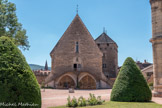 Cluny. <br> Le Farinier et la Tour du moulin derrière. La tour «lu moulin a été construite au tout début du XIIIe siècle. Accolée au farinier de l’abbaye, elle s’élève sur quatre étages. Un conduit maçonné dans le mur permettait de verser les grains directement depuis le farinier jusqu’au moulin. Le„ mécanisme du moulin est toujours visible au rez-de-chaussée; il était mis en mouvement par la rivière la Grosne.
Les grains utilisés pour fabriquer les farines provenaient de cultures faites à l’extérieur des murs de l’abbaye: avoine, épeautre et millet... Ces parcelles étaient entretenues par les doyennés placés sous la tutelle de l’abbaye.
La tour du moulin, par son emplacement sur l’enceinte, avait également une fonction défensive, le dernier étage est percé de meurtrières. Une salle au troisième étage, appelée salle des blasons, abrite une trentaine d’armoiries peintes sur l’enduit ou gravées.
