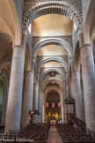 Saint-Philibert de Tournus. La nef<br> La voûte remarquable de la nef centrale a été montée dans la dernière partie du 11e siècle, remplaçant probablement un premier plafond ou un charpente. Une haute série de cinq berceaux transversaux est portée par des arcs diaphragmes polychromes à double rouleau. Ces arcs surmontent des demi-colonnes engagées à chapiteaux monolithiques de calcaire qui reposent à leur tour sur les piliers ronds. Cette voûte, contrebutée par le narthex à l’ouest et le transept à l’est, a permis l’ouverture de dix grandes fenêtres hautes inondant la nef de lumière sans risquer la stabilité de l’édifice. Cette solution remarquable est unique dans l’art roman, puisque elle a seulement été reprise dans l’église beaucoup plus modeste du Mont-Saint-Vincent.