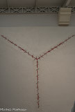 Le Signe.  Thomas Gleb (1912-1991)<br> Crépi, peinture et cordelettes.
Cette œuvre, conçue en 1979 pour la chapelle de Niort, fait partie d'un ensemble carmélite harmonieux avec un autel et une Porte de tabernacle. Le signe Y - initiale de YHVH et YESHOUA - a été sculpté comme une plaie rouge sang, refermée par des cordelettes évoquant des points de suture, à l'image d'une blessure en cours de cicatrisation. L'œuvre fut perçue par les moniales comme une 