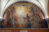 Au cœur du sanctuaire, la chapelle des Apparitions (XVIIe-XIXe siècles) <br>Le chœur est tel qu’à l’époque de Marguerite-Marie.  Et Jésus lui est apparu ─ en tout cas en ce qui concerne les trois grandes Apparitions ─ vraisemblablement à l’endroit où se trouve maintenant la peinture murale. C’est en 1966 que cette peinture fut achevée. Le centre représente l’Apparition du Christ à Sainte Marguerite-Marie. On y voit en particulier les détails relatés par la Sainte à propos de la deuxième grande Apparition mentionnée ci-dessus : le Seigneur, les bras en croix, « resplendissant de Gloire, les cinq plaies comme cinq soleils, et la plaie du Cœur comme une fournaise ardente ». En haut, à droite, nous reconnaissons la Sainte Vierge. Lui faisant face, à gauche, l’évangéliste Saint Jean, qui tient en sa main la Parole de Dieu, sous forme de rouleau. En dessous de la Sainte Vierge, l’Apôtre Paul qui tent dans sa main gauche le glaive de la Parole de Dieu. A gauche, en face, Saint François d’Assise, que Marguerite-Marie a vu dans une vision. Il montre en ses mains les stigmates de la Passion. A droite, en bas, les deux fondateurs de l’ordre de la Visitation, Saint François de Sales et Sainte Jeanne de Chantal. A gauche, en bas, debout, Charles de Foucauld. A genoux et regardant vers l’Apparition, Claude La Colombière. Quelques années plus tard, l’artiste (Luc Barbier) devait ajouter deux personnages. À genoux, à gauche, orienté vers nous, Saint Jean Eudes (17ème siècle) et à droite, le Père Matéo Crawley-Boevey, religieux du Pérou, mort en 1960.