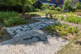 Derrière la maison de la mosaïque se découvre un jardin mosaïque. Ici les tesselles sont remplacées par des carrés de terre plantés de diverses essences.
Un cheminement en calades complète merveilleusement cet espace. Ce sont des galets posés verticalement sur un lit de sable et de chaux.