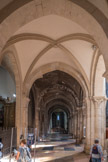 Les larges bas-côtés à voûtes d’arêtes sur doubleaux brisés reposant sur des pilastres cannelés des murs latéraux sont également romans. Les murs s’ouvrent sur les chapelles latérales, six au nord et cinq au sud, dans le style flamboyant des 15e et 16e siècles. A droite, chapiteau avec un arbre en Y.