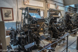 LINOTYPES.
En 1918, M. Faisy achète sa première linotype. Le procédé mécanique de cette machine consiste à fondre des lignes de caractères, appelées lignes-blocs.
Le linotypiste saisit une ligne de texte sur le clavier. Cette frappe libère les matrices des caractères correspondants, qui sont contenues dans le magasin. Une matrice est un moule en bronze portant en creux la gravure d’une lettre. Chaque matrice descend par un canal jusqu’au composteur. Quand celui- ci est rempli, on obtient alors le moule d’une ligne de texte. Après avoir vérifié sa ligne, le linotypiste envoie un alliage de plomb, d’antimoine et d’étain dans  cette ligne en creux. C’est un « saumon » qui alimente en alliage la linotype. Il est suspendu au-dessus du creuset chauffé à 280° pour le liquéfier. La ligne refroidie est ensuite éjectée sur un plateau (galée). On obtient alors une ligne complète du texte en relief. Simultanément, un bras récupère les matrices qui sont alors distribuées dans leur casier respectif grâce à un système de glissière rainurée qui détermine le bon parcours à suivre et le bon magasin à atteindre.