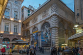 Place Banchi.  La place fut dévastée par un terrible incendie en 1398 et c'est seulement au XVIe siècle que fut terminée la restauration de ses édifices, qui comprenait la construction d'une Loggia dei mercanti (Loggia des marchands) selon un projet d'Andrea Ceresola dit le Vannone, destinée à donner un toit aux banquiers et aux agents de change qui travaillaient dans le quartier. Elle est construite entre 1589 et 1595 pour répondre à la florissante économie de sa république. La loggia était composée d'un unique local à plan rectangulaire avec des ouvertures à arcades délimitées de colonnes jumelées. À l'extérieur, la façade présente des sculptures de mascarons placées aux centres d'arcs surmontés de bas-reliefs aux motifs ornementaux (casques, blasons, trophées guerriers). 

A partir de 1855, elle devint le siège de la première Borsa Merci e Valori (Bourse d'échange de marchandises et de valeurs) en Italie, transférée en 1922, piazza De Ferrari.