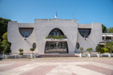 La Grande-Motte. <br> La mairie est inaugurée le2 décembre 1982. Jean balladur : « J’ai fait trôner sur la place l’Hôtel de Ville … dans l’axe au RDC l’accueil des visiteurs, à l’étage la salle des mariages… En démocratie , les citoyens doivent primer les élus . De part et d’autre de cette primauté axiale, le bureau du maire et la salle du Conseil municipal. La découpe elliptique des baies exprime cette hiérarchie sur la façade… Pour moi un bâtiment public doit être un signal adressé aux habitants comme aux visiteurs ».