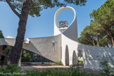 La Grande-Motte. <br> La construction de l'église Saint-Augustin commence en 1975. Son plan est un entrecroisement de paraboles, un trait cher à l'architecte Jean Balladur. Sa conception est ingénieuse elle peut accueillir le surplus de fidèles lors de la saison estivale. En effet, les vitraux de son chœur sont montés sur des gongs et s'ouvrent largement vers l'extérieur permettant au prêtre de célébrer l'office sous les pins parasols.