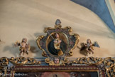 Saint-Sauveur-sur-Tinée <br> L'encadrement s'interrompt au sommet pour accueillir un médaillon daté de 1744, figurant une Vierge de Douleur au cœur percé d'une dague, entouré d'un double rameau fleuri, porté par un séraphin et flanqué de deux angelots.