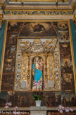Saint-Sauveur-sur-Tinée <br> Le panneau central présente une sorte de portique dont la niche est cantonnée de deux pilastres en saillie, ornés de chutes de feuillages suspendues à des séraphins, que prolongent des ailes décorées de rinceaux symétriques et que surmonte une architrave aux mêmes motifs. En couronnement deux angelots dévoilent un baldaquin abritant la colombe de l'Esprit Saint. Le fond du panneau développe deux élégantes guirlandes fleuries qui se retrouvent sur la plinthe à la base. Les mystères de la vie de Marie sont figurés en trois séries de cinq : mystères joyeux pour l'Enfance du Christ, douloureux pour sa Passion et glorieux pour l'apothéose qui suit la Résurrection.