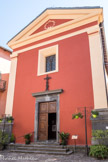Saint-Sauveur-sur-Tinée <br> Eglise Saint-Michel Archange. La façade d'entrée se contente de deux pilastres d'angles en maçonnerie sur base de pierre portant une architrave que surmonte un fronton triangulaire doté d'un simple motif stuqué. Le portail s'érige au sommet d'un court emmarchement et présente un motif d'encadrement de pierre à double mouluration lisse, dans le goût rigoureusement classique de la fin du XVIIIe siècle.