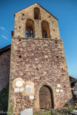 Roure. <br>L’église romane. La partie inférieure de ce clocher-porche est constituée d’un appareillage de blocs de tailles hétérogènes, à joints plutôt larges. Les chaînages d’angle sont en tuf à joints fins.
La partie supérieure, en léger retrait, est constituée d’un fronton triangulaire formant un clocher-peigne, percé de trois baies, appareillé en blocs de tuf rectangulaires, soigneusement taillés, aux joints très fins. Ces deux parties sont séparées par une corniche de tuf saillante, à tranche arrondie. Les deux registres semblent contemporains (XIVe siècle ) l’un de l’autre. Le portail actuel constituait la porte d’entrée de l’église médiévale. Il est formé d’un arc en blocs de tuf. La façade est ponctuée de trous de boulins qui servaient à l’établissement des échafaudages.