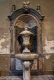 <center>Eglise Saint Théodore</center>Le baptistère est situé à droite en entrant. La composition d’ensemble évoque une fontaine jaillissante. La cuve baptismale fait partie d'un ensemble joliment sculpté en marbre polychrome (XVIIIe s.). Cet ensemble est composé d'un portique à coquille, fond en cul de four, cintré, dont la clef est surmontée de têtes d'angelots, entourés de pots à feu.