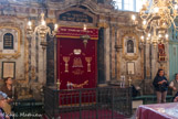 <center>La Synagogue</center>Au centre, travée de colonnes cannelées d'ordre ionique et au-dessus une corniche cintrée formant fronton ; travées latérales, lambris représentant un panneau couronné par un baldaquin.