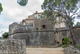 <center>Le château de Saumane.</center> La topographie se prêta particulièrement à la création au Moyen Âge d'un site perché, défendu par une enceinte, et doté d'un premier château de type féodal dont subsistent d'intéressants vestiges dans la partie méridionale de l'éperon. L'établissement du castrum bénéficia, en outre, de la qualité de la pierre (calcaire gréseux) formant l'éperon et qui entraîna la création d'une carrière qui restera active durant plusieurs siècles. C'est dans le courant du XIVe siècle qu'une maison des cardinaux est édifiée au nord du castrum et en limite de l'enceinte castrale. Ce bâtiment imposant, de 30m sur 8m, s'élevait sur trois niveaux et rappelle en tout point les demeures luxueuses construites par les cardinaux, à Avignon et dans les campagnes environnantes, durant le séjour des Papes au XIVe siècle. Ce palais est visible actuellement depuis l'esplanade sud. A l'origine, une terrasse crénelée coiffait le monument selon l'usage. Cette partie a été remplacée en 1582 par une toiture à quatre pentes animée de lucarnes, parti architectural plus conforme aux critères de la Renaissance.