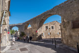 Castries. <br> L'aqueduc. Il a une longueur totale de 6822 mètres pour un dénivelé de 3 mètres, soit une pente moyenne de 0, 447 mètre par kilomètre. Le trajet choisi fut donc celui de la courbe de niveau, même si elle allongeait beaucoup la longueur de l'aqueduc. Cela évitait d'avoir à construire un aqueduc entièrement supporté par des arcades.  Il semblerait que pour éviter un courant d'eau trop rapide qui aurait rapidement érodé la pierre tendre de Castries utilisée pour construire la conduite, la rigole fut construite en escalier hydraulique, c'est-à-dire en plusieurs sections de très faible pente se terminant sur un puits carré qui servait d'escalier mais aussi, grâce au tourbillon causé, à faire précipiter le carbonate de calcium contenu dans l'eau qui se déposait au fond du puits avec toutes sortes d'impuretés au lieu de finir, par ses dépôts, par diminuer la section du conduit au bout de plusieurs années.