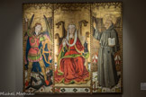 Musée Hyacinthe Rigaud. <br> Maître des Florida (école aragonaise)
Triptyque Spiridon
Vers 1450-1475
peinture à la détrempe et fond d’or sur bois. 
Ce triptyque fait partie d’un retable plus imposant. Il est attribué à l’un des meilleurs peintres aragonais, le Maître des Florida. À gauche, Saint Michel terrasse le dragon, au centre Marie-Madeleine en majesté sur un trône gothique tient de la main gauche un flacon à parfum. Au-dessus d’elle, une modification du panneau a fait disparaître un Christ en croix dont il ne reste plus que le visage auréolé et le haut de la croix. À droite, Saint Bernardin de Sienne. La finesse du travail sur l’armure de saint Michel évoque l’influence du peintre flamand Van Eyck, qui aurait séjourné à Valence, haut-lieu de la création artistique de ce temps.