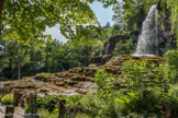 Le Jardin des Fontaines Pétrifiante<br>En provenance du plateau des Chambarans quelques ruisseaux se perdent dans le sol très calcaire de la plaine de St-Marcellin. Durant leur trajet souterrain ces eaux chargées de dioxyde de carbone circulent sous pression à travers les couches de roches. Cette particularité leur confère une légère acidité qui leur permet de dissoudre très facilement le calcaire. Dès leur apparition à l'air libre le gaz s'échappe, le calcaire dissout réapparait et se dépose sur le premier obstacle rencontré.
En particulier sur les mousses qui sont recouvertes à la base mais continuent de pousser. Le tuf est le nom donné à cette roche formée par des végétaux pétrifiés. Ces sources renferment plus de 315 mg /I de calcaire. Cette propriété permet au tuf de s'accroître de plusieurs centimètres par an